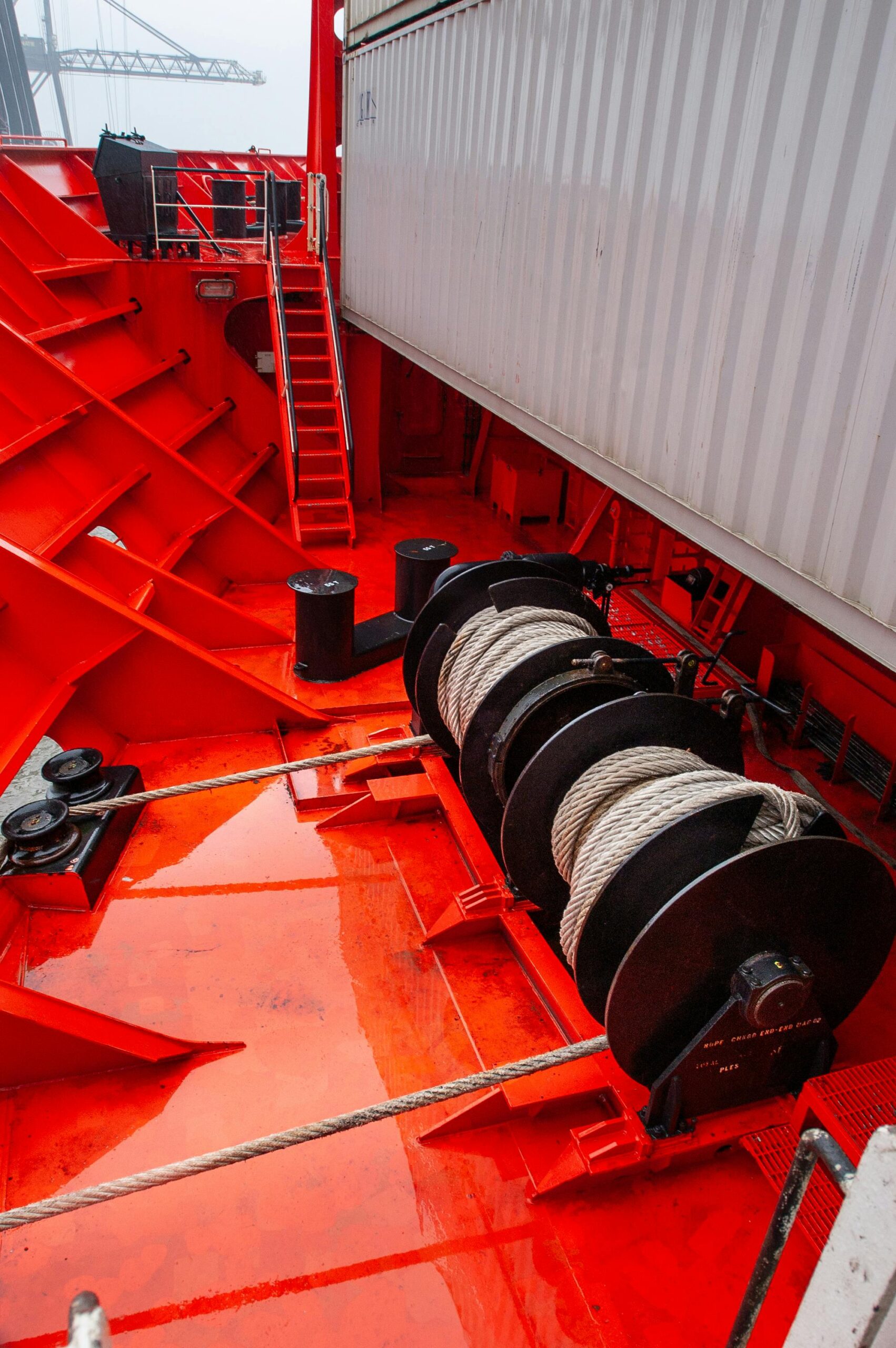 project-3 Close-up of a vibrant red ship deck featuring mooring equipment and marine ropes.